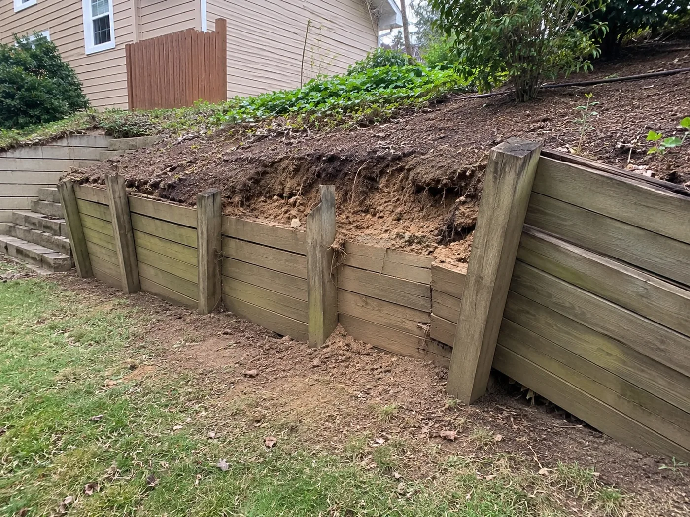 A residential retaining wall showing signs of leaning and shifting blocks in need of repair